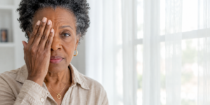 glaucoma — woman testing her own vision by covering one eye